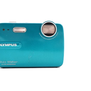 May include: A teal Olympus Stylus Water 3m/10ft waterproof digital camera with a black strap.