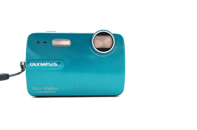 May include: A teal Olympus Stylus Water 3m/10ft waterproof digital camera with a black strap.