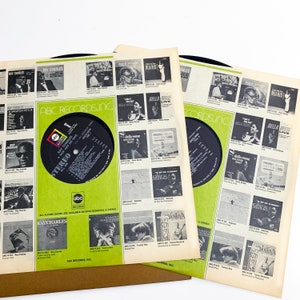 Pu&ograve; includere: Tre album di dischi in vinile vintage con copertine con Ray Charles e altri artisti. Le copertine sono bianche con accenti verdi e neri, che mostrano l'artwork e il testo dell'album. I dischi sono neri.