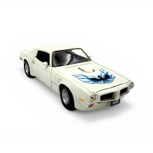 May include: A white model car with a blue and black graphic on the hood. The car has black wheels and a black interior. The car has the words "TRANS AM" on the side.