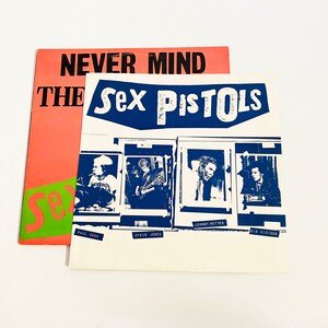 May include: A white record album cover with the text "Sex Pistols" in blue and white. The album cover features four black and white photos of the band members, with their names printed below each photo. The album cover is titled "Never Mind The Bollocks, Here's The Sex Pistols".