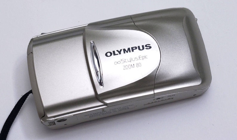 Silver Olympus camera lens cover