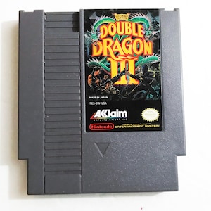 May include: A gray Nintendo Entertainment System game cartridge for Double Dragon III: The Sacred Stones. The front of the cartridge features a colorful illustration of the game's characters and a dragon.