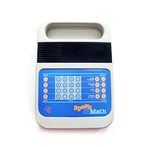 May include: A vintage Speak & Math educational toy. The device has a white and blue color scheme with a handle at the top. It features a keypad with numbers and math symbols, along with function buttons and the text "Speak & Math".