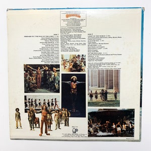 May include: The back cover of a vinyl record for the musical "Godspell". The cover features a collage of images from the musical, including a man in a red and yellow costume, a group of people singing, and a cityscape. The text on the cover includes the title of the musical, the composer's name, and the names of the actors and actresses who appear in the musical.