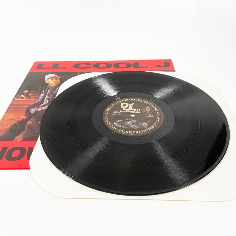 May include: A black vinyl record with a red, white, and black album cover. The album cover features the text "LL COOL J" in large, bold letters. The record label is "Def Jam Recordings".