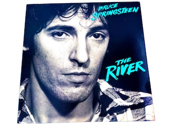 May include: A black and white photo of Bruce Springsteen on the cover of his album "The River". The album title is in a turquoise blue font.