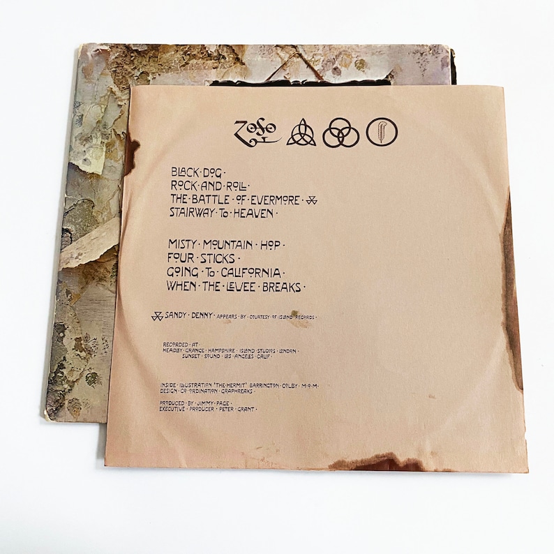 May include: A vintage vinyl record album cover for Led Zeppelin's album "Houses of the Holy". The cover features a brown background with the band's name and album title printed in brown text. The album's tracklist is printed in brown text on the right side of the cover.