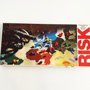 May include: A vintage Risk board game box with a red, white, and blue cannon on the front. The box features a world map with colorful plastic pieces representing armies. The text "Parker Brothers World Conquest Game" and "RISK" are printed on the box.