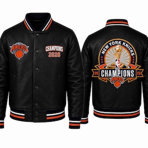 Pode incluir: Uma jaqueta varsity preta com o logotipo dos New York Knicks e o texto Champions 2026 na frente. As costas exibem um gráfico grande com um troféu, o texto New York Knicks e Champions 2026. Possui acabamento canelado com listras.