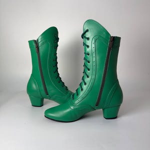 Puede incluir: Un par de botas de media caña en color verde vibrante. Estas botas cuentan con cordones frontales de color verde oscuro, cierre de cremallera lateral, punta redondeada y un tacón bajo de bloque. Incluyen costuras decorativas y perforaciones.