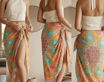 May include: A cream-colored halter top paired with a colorful sarong. The sarong features a vibrant pattern with shades of yellow, pink, and turquoise. The sarong is tied at the waist, creating a high slit. The outfit is suitable for beachwear or resort wear.
