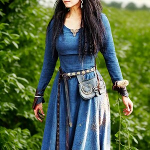 May include: A long-sleeved, blue dress with a V-neck and a flowing skirt. The dress is accessorized with a brown leather belt, a small pouch, and wrist cuffs. The dress has a medieval or fantasy theme.