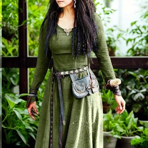 May include: Olive green medieval-style dress with long sleeves and a flowing skirt. The dress features a scoop neckline and is accessorized with a brown leather belt, a small pouch, and wrist cuffs. The outfit is suitable for cosplay or historical reenactments.