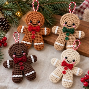 May include: Four crocheted gingerbread person ornaments in varying shades of brown and beige. Each figure features a stitched smile, pink cheeks, two small buttons on the torso, white icing-style trim on the limbs, and a red and white hanging loop.
