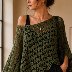 May include: An olive green crochet poncho featuring an openwork pattern with a wide, loose weave. The garment has a wide neckline and long, flowing sleeves, layered over a solid black top. The crochet design consists of repeating circular motifs.