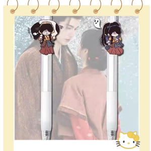 May include: Two white pens with cartoon character toppers. The toppers feature a cartoon girl in a traditional outfit, with a black creature and a ghost. The background shows a couple in traditional clothing.