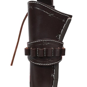 May include: A brown leather holster with white stitching and a loop for a belt. The holster has a cartridge holder and a leather tie. The design includes decorative stitching.