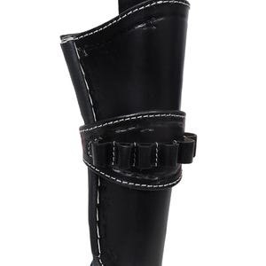 May include: Black leather holster with white stitching. Features a loop for a belt and a band with multiple loops for ammunition. The holster is designed to hold a firearm.