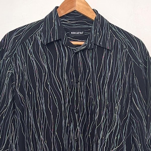 May include: Black shirt with a vertical wavy pattern in white, blue, and green. The short-sleeved shirt has a collared neckline and is buttoned down the front. The brand name is visible on the collar.