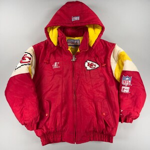 May include: Red hooded jacket with yellow lining and white and yellow accents. Features the Kansas City Chiefs logo on the chest and sleeve, with "NFL Pro Line" branding. A vintage, zip-up, winter coat.