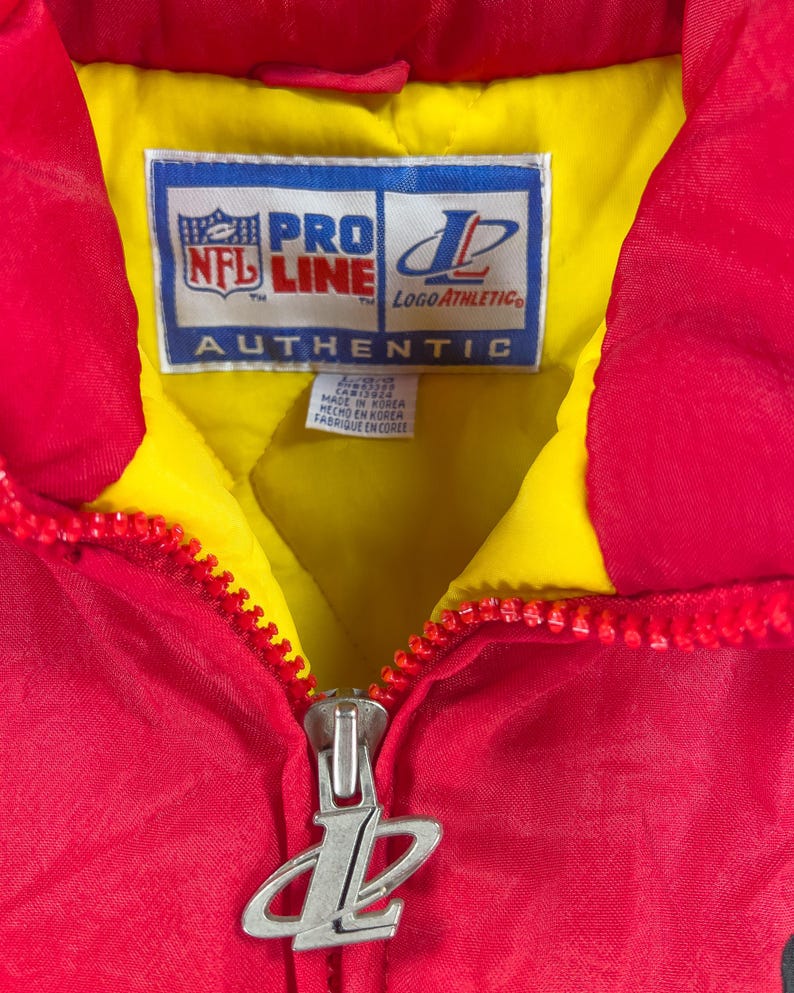 May include: Red and yellow vintage jacket with a full zipper. The jacket features the NFL Pro Line and Logo Athletic logos. The tag reads "AUTHENTIC" and "MADE IN KOREA".
