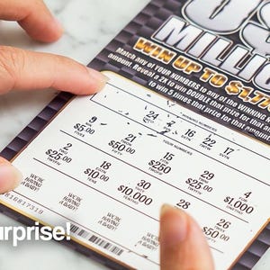 May include: A lottery ticket with the text "US MILLIONS" and the potential to win up to $1,776,000. The ticket is being scratched to reveal the winning numbers. The word "Surprise!" is printed on the bottom left.