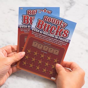 May include: Two "Bounty Bucks" scratch-off lottery tickets. The tickets have a red and blue design with the text "OVER $1 MILLION IN PRIZES!" and "$10". The tickets feature sheriff star symbols and the word "WANTED".