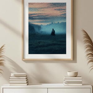 May include: Framed art print depicting a solitary figure in a field at dusk. The artwork features a color palette of blues, greens, and pinks, with a textured, painterly style. The frame is a light wood tone.