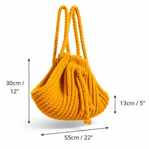 May include: Mustard yellow knitted tote bag, measuring 30cm high, 55cm wide, and 13cm deep. The bag features two braided handles and a gathered design. The bag is made of a thick, textured yarn.