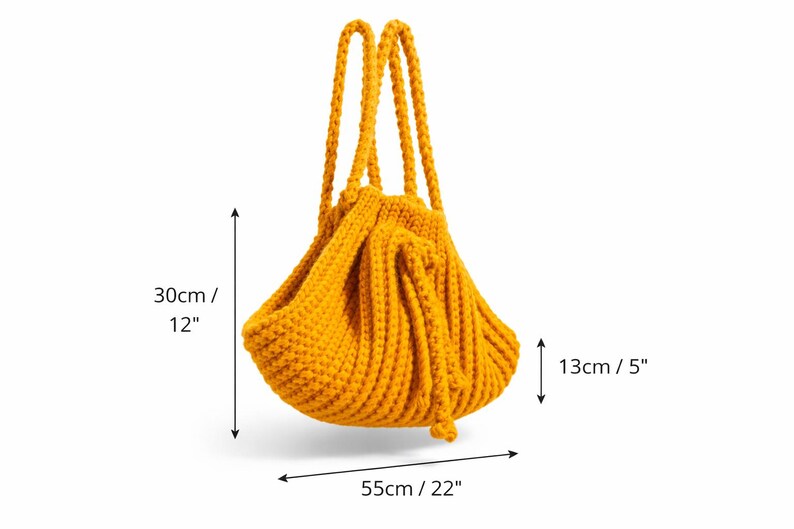 May include: Mustard yellow knitted tote bag, measuring 30cm high, 55cm wide, and 13cm deep. The bag features two braided handles and a gathered design. The bag is made of a thick, textured yarn.