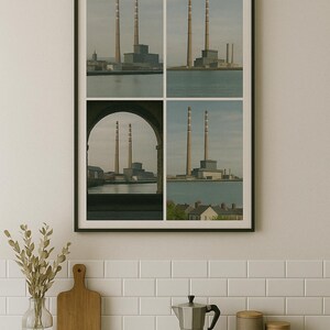 May include: A framed print featuring four images of a power plant with tall smokestacks. The images are set against a backdrop of water and sky. The print is displayed above a kitchen counter with a cutting board, vase, and coffee maker.