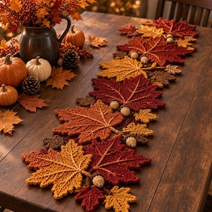 May include: A crochet table runner featuring a series of interconnected maple leaves in shades of red, orange, and yellow. The runner is decorated with small, crocheted acorn accents nestled between the leaves, creating a textured autumn-themed design.