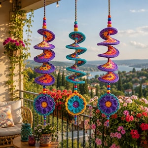 May include: Three hanging spiral ornaments crafted from multicolored crochet yarn. Each piece features a series of purple, orange, and teal spiraling discs suspended by a cord with small beads, ending in a large, detailed crochet flower.