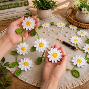 May include: A close-up of a handmade crochet daisy chain. The daisies have white petals and yellow centres, connected by green stems and leaves. The chain is displayed on a neutral surface, highlighting the intricate floral design.