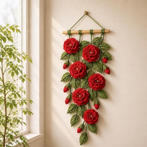 Può includere: Un arazzo da parete fatto a mano con una cascata di rose e boccioli rossi all'uncinetto, con foglie verdi. La composizione floreale è sospesa a un tassello di legno con uno spago verde. Questo pezzo decorativo aggiunge un tocco di fascino ispirato alla natura.
