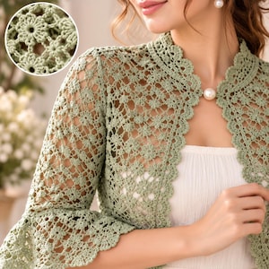 Può includere: Un bolero all'uncinetto color verde salvia caratterizzato da un intricato motivo floreale con design traforato, maniche lunghe con polsini svasati, collo alto e una chiusura con un singolo bottone a perla bianca sullo scollo, con dettaglio circolare.