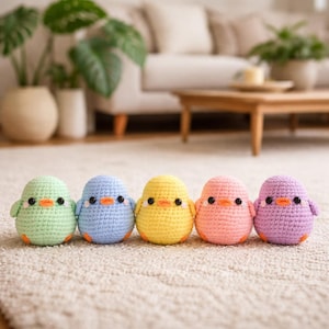 Könnte beinhalten: Fünf gehäkelte Küken in einer Reihe, jedes in einer anderen Pastellfarbe: Grün, Blau, Gelb, Rosa und Lila. Sie haben orangefarbene Schnäbel und kleine schwarze Augen. Die Küken sitzen auf einem hellen Teppich.