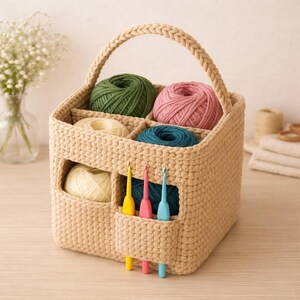 May include: A beige crochet yarn storage basket with a handle, holding various colored yarn balls: green, pink, cream, and teal. Three crochet hooks in yellow, pink, and blue are in a side pocket. A craft organizer.
