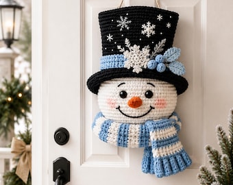 Peut inclure: Une décoration murale en crochet représentant un bonhomme de neige avec un haut-de-forme noir orné de flocons blancs, un ruban bleu clair et des baies bleues. Le visage est blanc avec des yeux noirs, un nez orange, des joues roses et une écharpe rayée.