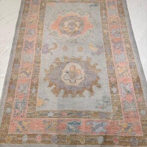 May include: A rectangular area rug with a light blue central field and a detailed border. The rug features floral and geometric patterns in shades of peach, brown, and blue. The rug's design is symmetrical, with a central medallion and corner accents.