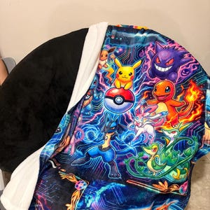 以下が含まれることがあります： ピカチュウ、ゲンガー、ルカリオなどの様々なポケモンキャラクターが、デジタル回路図のようなダークブルーの背景に描かれた、鮮やかなマルチカラーのグラフィックプリントが特徴のプラッシュブランケット。裏面は無地の黒と白の配色です。