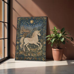 May include: A framed tapestry featuring a white unicorn with a golden horn, set against a night sky with stars and a cityscape. The tapestry has a blue background with floral borders and is displayed near a window and a potted plant.