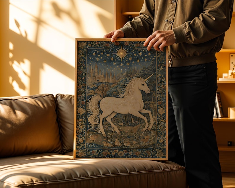 May include: A framed tapestry featuring a white unicorn with a golden horn, set against a night sky with stars and a castle. The artwork has a detailed, vintage style with a gold frame, creating a whimsical and enchanting scene.
