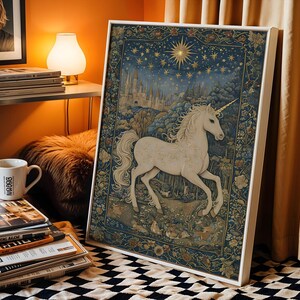 May include: A framed tapestry featuring a white unicorn in a forest setting under a starry night sky. The artwork has a detailed, vintage style with a white frame. The color palette includes blues, greens, and gold.