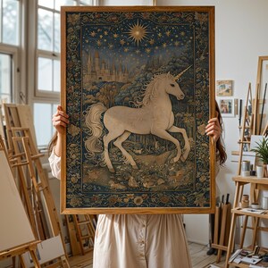 May include: A framed tapestry featuring a white unicorn with a long flowing mane and tail, set against a backdrop of a castle, forest, and starry night sky. The artwork is framed in a natural wood frame.