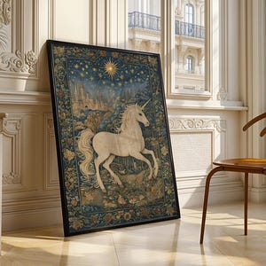 May include: Framed artwork featuring a white unicorn with a flowing mane and tail, set against a backdrop of a starry night sky and a castle. The artwork is framed in black and leans against a wall in a well-lit room.