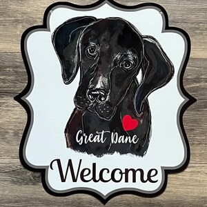 May include: A white welcome sign with a black and white illustration of a Great Dane dog with a red heart. The sign says "Great Dane" and "Welcome".