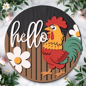 May include: A round wooden sign with a rooster design and the word "hello" in white script. The rooster is red, yellow, and green, with a brown fence background. A white flower with an orange center is also featured.