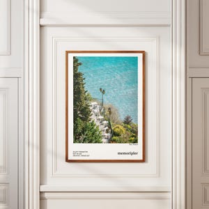 Póster vertical mate con fotografía, terraza junto al mar, plantas mediterráneas, valla de hierro forjado, ambiente tranquilo, elegancia costera.